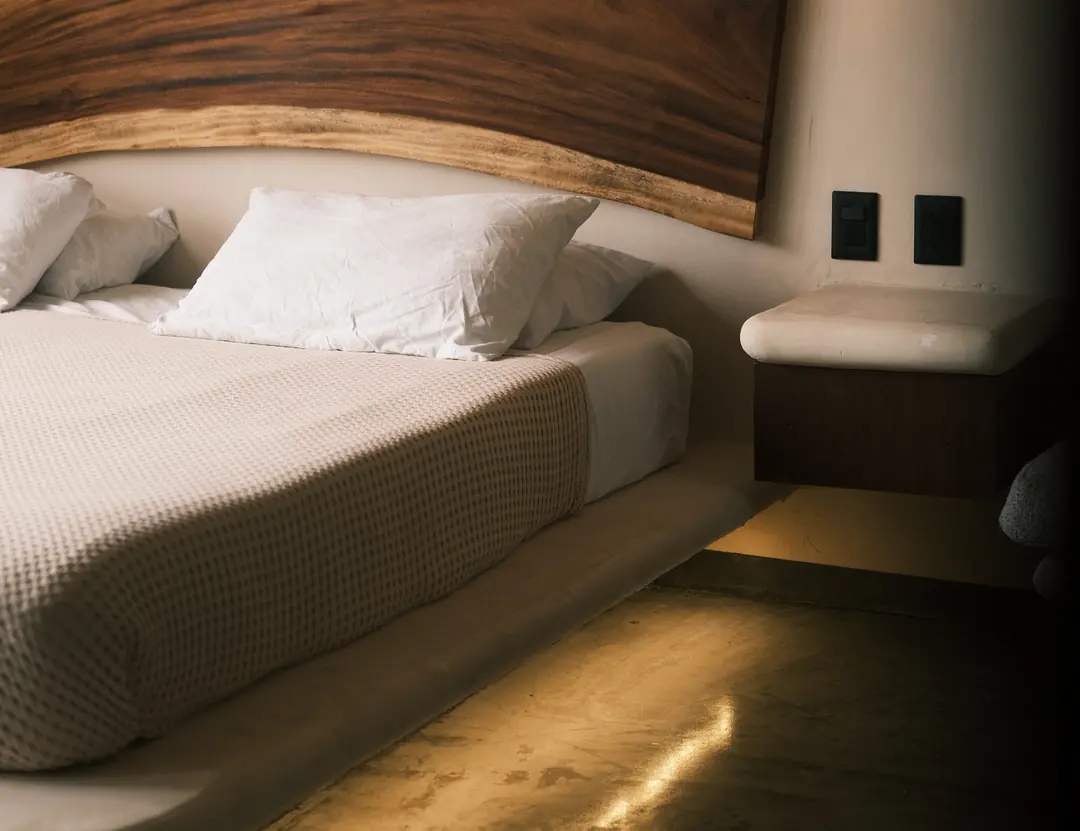 Une chambre d’hôtel au lit bas, éclairée par en dessous.